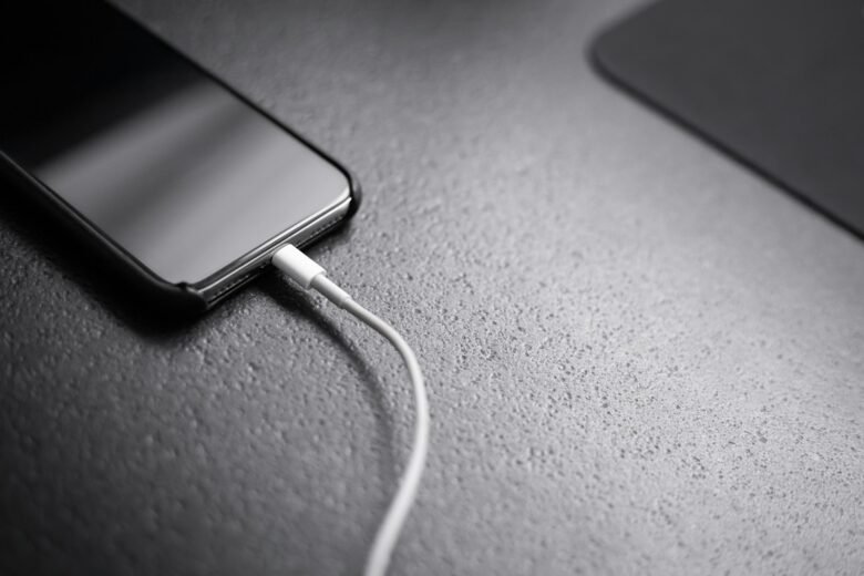 Smartphone connected to a charging cable on a desk