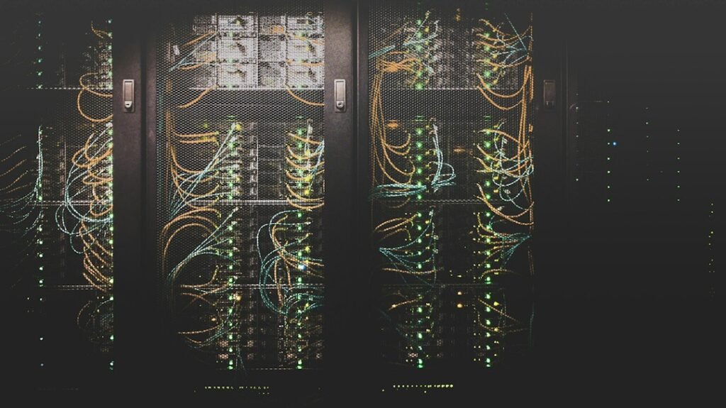 Server and networking equipment with cables and indicator lights behind rack doors