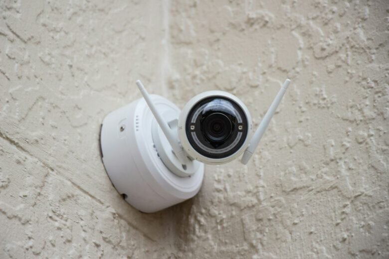 White outdoor security camera mounted on a textured wall