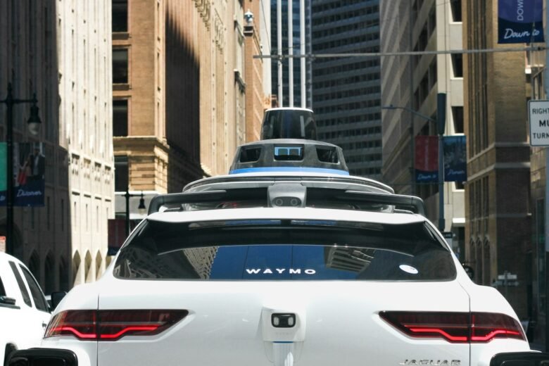 Rear of a white Waymo-branded Jaguar vehicle with roof-mounted sensors on a city street; illustrative photo, not Singapore