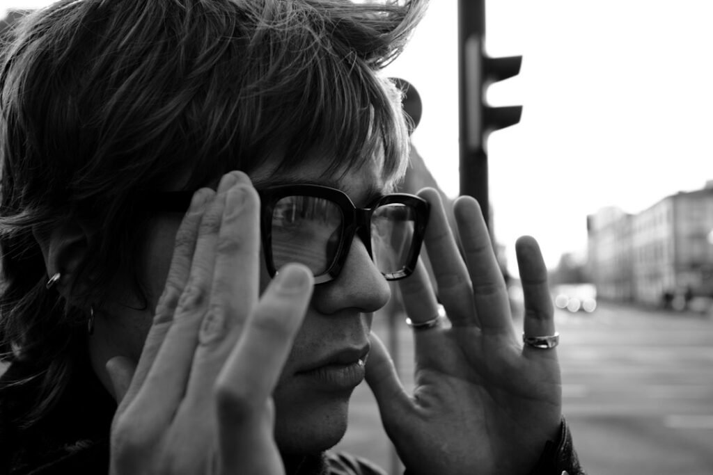 Person adjusting dark glasses on a city street, illustrating public-space privacy concerns around wearable cameras. Photo by Daniil Velychko on Unsplash.
