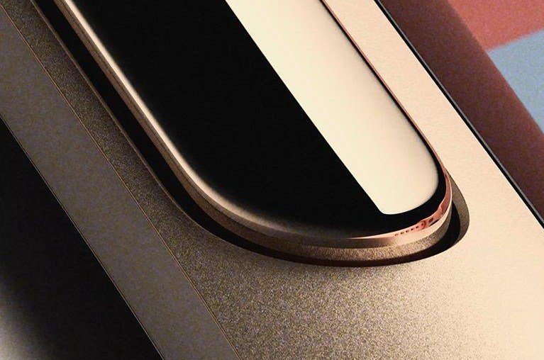 Close-up of the Google Fitbit Edge showing its metal case, orange side button, display edge and band. Image: Google via The Verge.