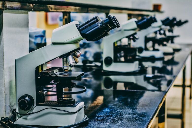 A row of optical microscopes on a laboratory bench