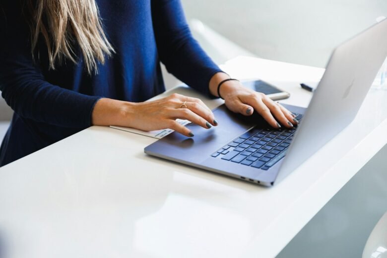 Person typing on a MacBook at a bright office desk while working with email. Photo by Luke Southern on Unsplash.