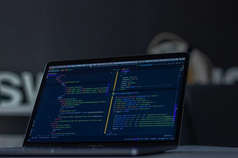 A laptop displaying source code in a dark-themed editor. Photo by Arnold Francisca on Unsplash.