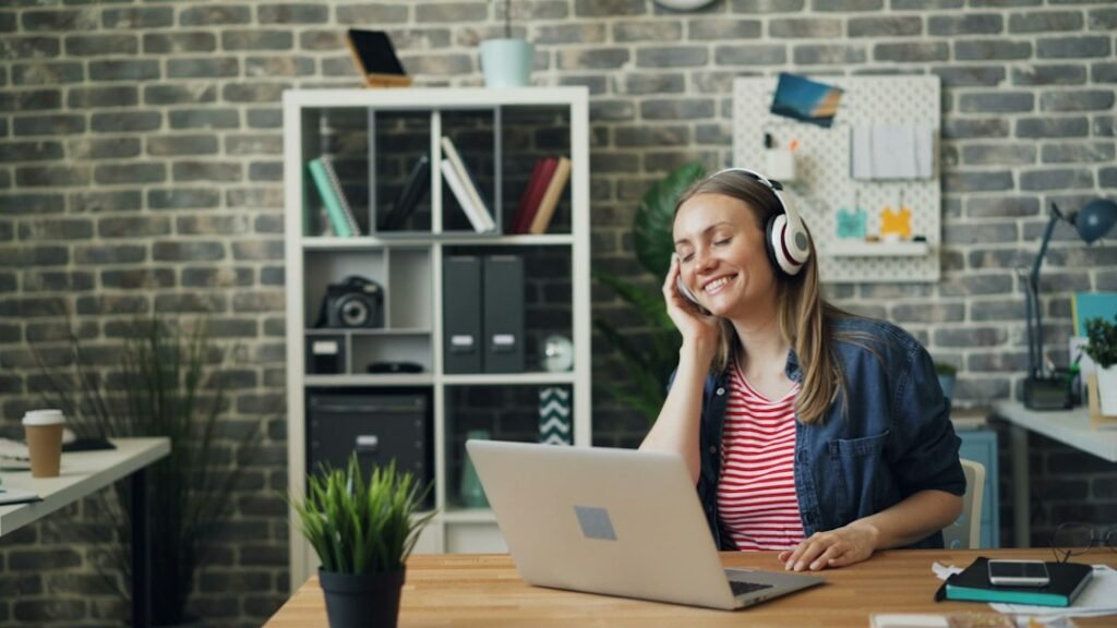 Woman wearing boomless over-ear headphones while working on a laptop in an office