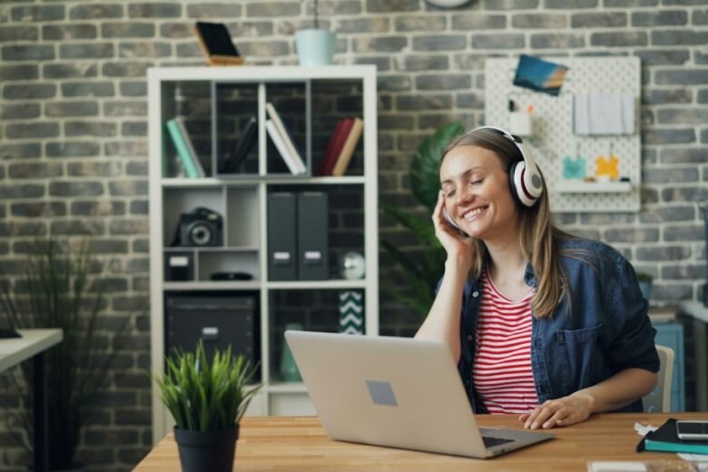 Woman wearing boomless over-ear headphones while working on a laptop in an office