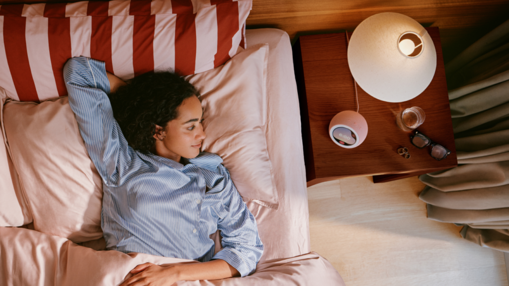 Amazon Echo Time smart alarm clock on a bedside table next to a person in bed
