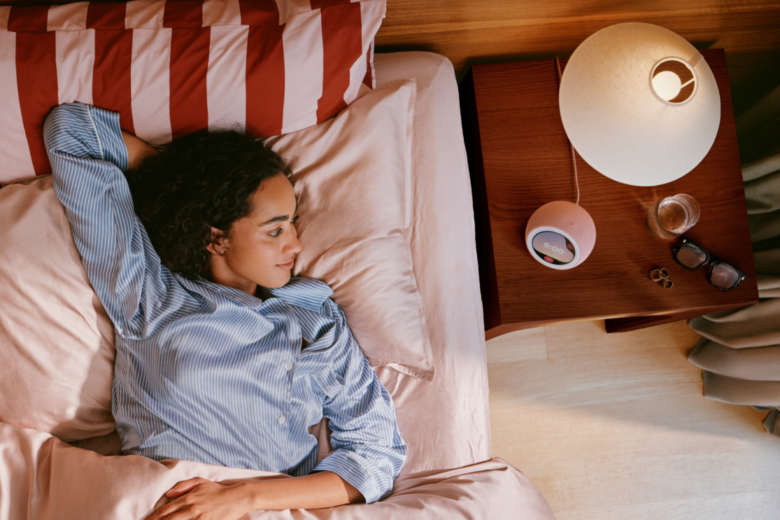 Amazon Echo Time smart alarm clock on a bedside table next to a person in bed