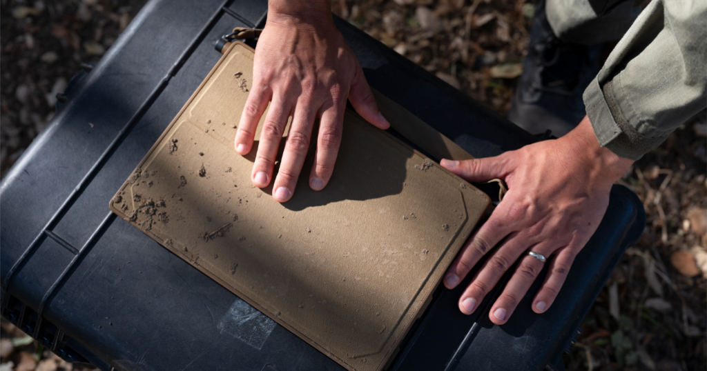 Mud-covered Anduril BlueChip rugged laptop on an equipment case