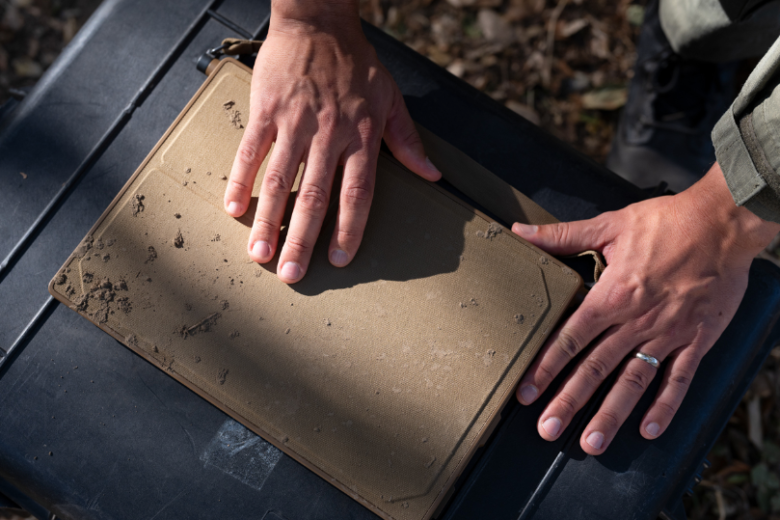 Mud-covered Anduril BlueChip rugged laptop on an equipment case
