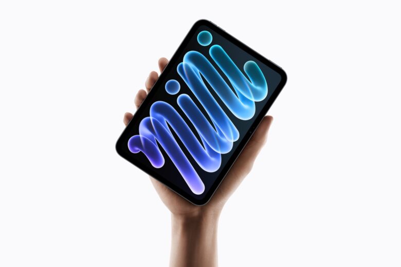 Apple iPad mini with an OLED display held in one hand against a dark background